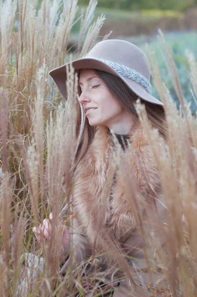 Donna in pelliccia beige nel campo asciutto autunnale — Foto Stock