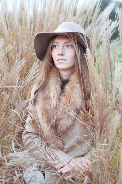 Woman in beige fur coat in the dry autumn field — Stock Photo, Image