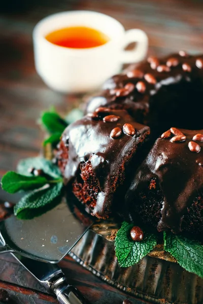 Sweet chocolate cake with cacao icing and decorated with mint — Stock Photo, Image