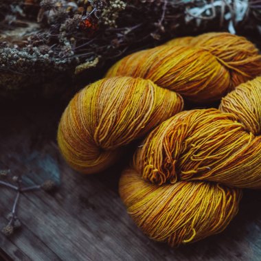 Bright yellow wool yarn skeins in rustic background