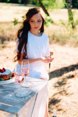 Yaz nişan pikniği. Masada oturan genç gelin akşam yemeği için servis yapıyor..