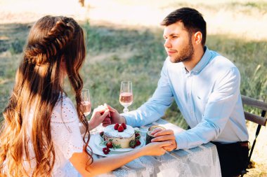 Bir çift sevgili, dışarıda yemek masasında nişanlarını kutluyorlar. 