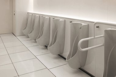 Pisuarlar beyaz ve temiz erkekler tuvaletinde sıraya girdiler.
