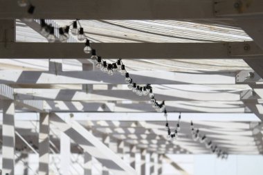 Beyaz bir sahil evinin soyut konsept fotoğrafı. Kablolarla süslenmiş klasik ampulleri var. Yazı hissetmeni sağlıyor.