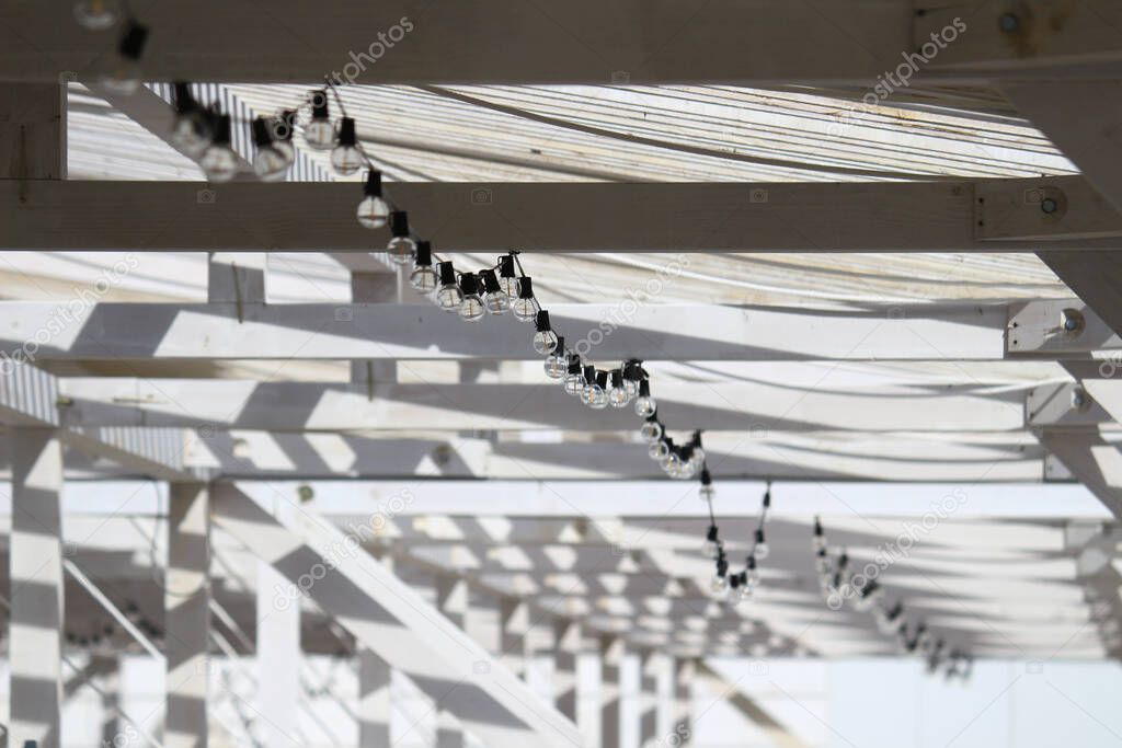 Abstract concept photo of a white beach house with vintage light bulbs decorated with cables that makes you feel summer