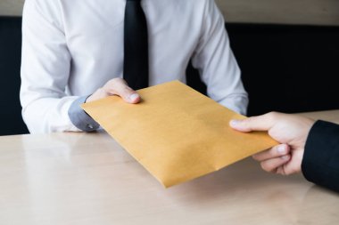İş adamı, rüşvet parasını kahverengi bir zarfla alır. Ofiste başka bir adam, rüşvet ve yolsuzluk kavramı oluşturur..