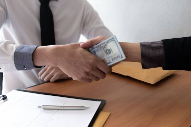 Ofis odasında el sıkışan ve rüşvet alan iki işadamı, rüşvet ve yolsuzluk kavramı.