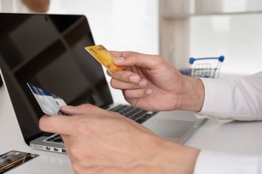 Kredi kartı tutan, internetten alışveriş yapan bir adamın eli..