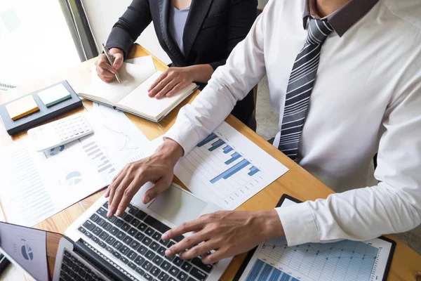 Two business people are discussing about business graph on the table in the office room. business discussing and planning strategy, concept.