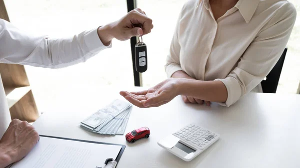 Car sales representative gives the key to customer after signed the sale contract in the office, Car rental concept.