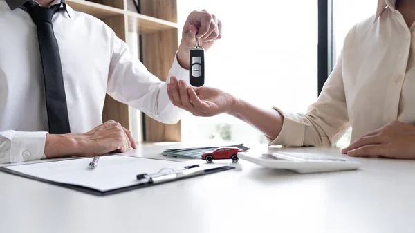 Car sales representative gives the key to customer after signed the sale contract in the office, Car rental concept.