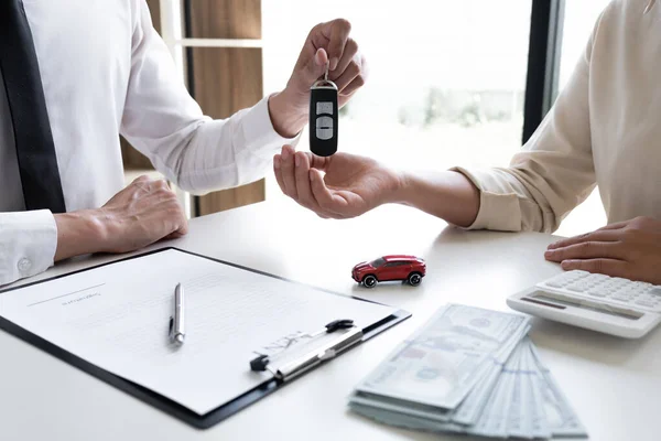 Car sales representative gives the key to customer after signed the sale contract in the office, Car rental concept.