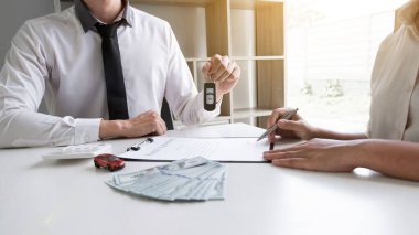 Araba satış temsilcisi, araba kiralama konseptini imzaladıktan sonra anahtarı müşteriye verir..