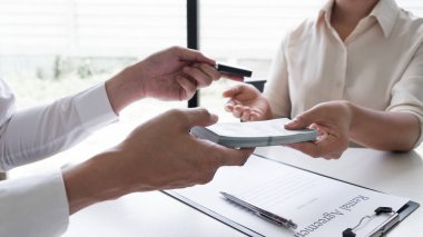 Araç kiralama temsilcisine kiralama ücretini müşteri ödüyor. Ofiste araba kiralama sözleşmesi imzalamış. Araba kiralama konsepti..