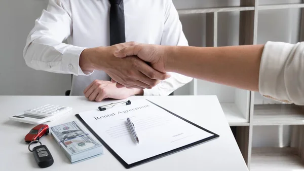 Car sales agent and client shaking hand after finishing signed the car rental agreement in the office, Car rental concept.