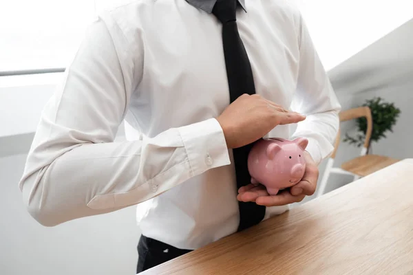 Businessman protecting piggy saving in hands. financial, save money concept.