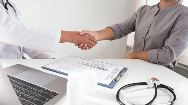 Doktor ve hasta bir adam ofis odasında tokalaşıyor. Tıbbi ve sağlık hizmetleri kavramları..  