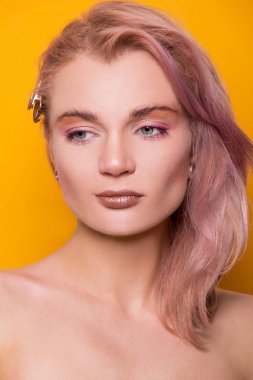 Portakal rengi bir arka planda izole edilmiş güzel Avrupalı model bir kızın parlak altın rengi makyajı.