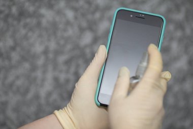 Kadının eli cep telefonuna alkol, dezenfektan spreyi sıkıyor, Covid-19 virüsü enfeksiyonunu önlüyor, mikrop ya da bakteri bulaşmasını önlüyor, ortadan kaldırmak için silmek ya da temizlemek için telefon kullanıyor, Coronavirus salgını