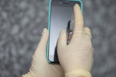 Kadının eli cep telefonuna alkol, dezenfektan spreyi sıkıyor, Covid-19 virüsü enfeksiyonunu önlüyor, mikrop ya da bakteri bulaşmasını önlüyor, ortadan kaldırmak için silmek ya da temizlemek için telefon kullanıyor, Coronavirus salgını