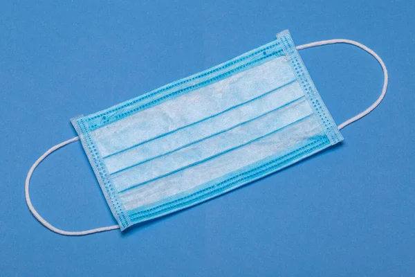 Protective medical mask isolated on a blue background. Protective masks as precaution in spread of coronavirus Covid-19