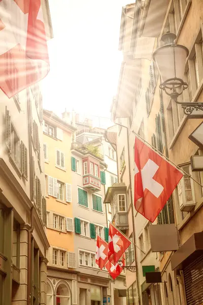 Old street with swiss flags, sunrays — Stock Photo, Image