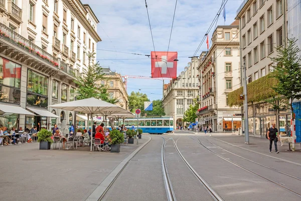 Curych, nákupní ulice Bahnhofstrasse s tramvají a švýcarská vlajka — Stock fotografie