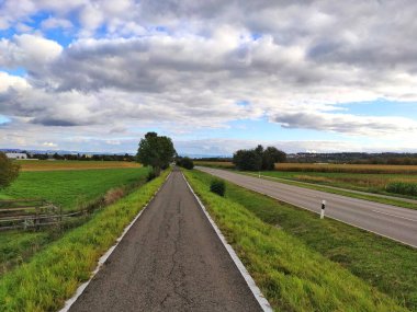 Kırsal arazide mavi gökyüzü ve bulutlarla kırsal yol