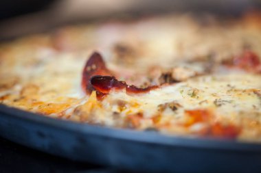 Otantik ev yapımı lezzetli pizza yakın pastırma, peynir ve domates bulanık arka plan ile mutfakta plaka üzerinde çekim