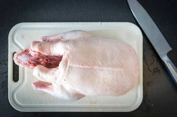 raw duck meat on cutting board with knife on kitchen table