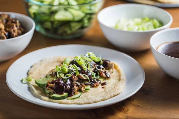 Peking Duck served with fresh cucumber, plum sauce, green onion and roasted wheaten chinese pancakes  on wooden table