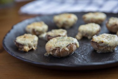 karanlık taş plaka üzerinde mavi peynir ile doldurulmuş champignon mantar Gratine