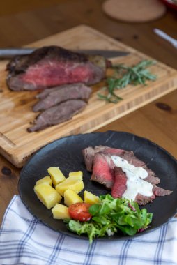 Dilimlenmiş ve patates ve taş plaka üzerinde taze sebze ile servis lezzetli etli nadir kızartılmış sığır eti biftek