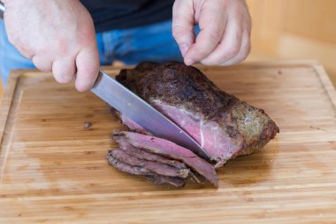 Ahşap kesme tahtası üzerinde bıçak ile sulu kızartma beaf Dilimleme