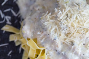 Makarna bir close-up mutfakta karanlık plaka üzerinde peynir sos ile