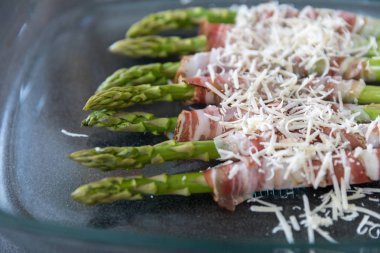 Izgara yeşil kuşkonmaz pastırma ve siyah pan zemin üzerine Parmesan peyniri ile sarılmış