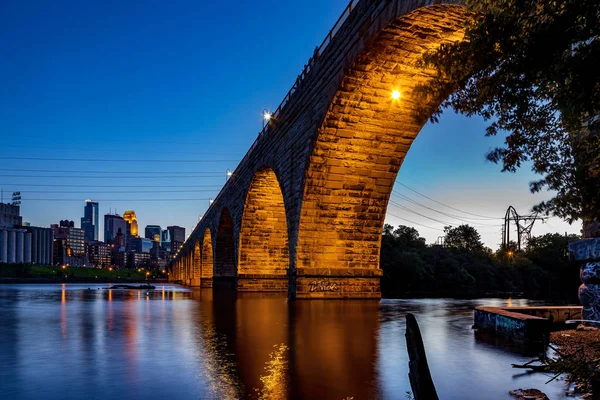 Blick auf die schöne steinerne Bogenbrücke von Minneapolis, mn, usa in der Abenddämmerung Stockfoto