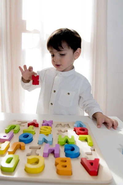 Kid praktijk lezen kijken naar houten letters op de tafel — Stockfoto