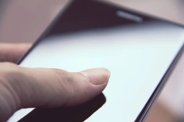 Mano que sostiene el teléfono inteligente móvil con pantalla en blanco . — Foto de Stock