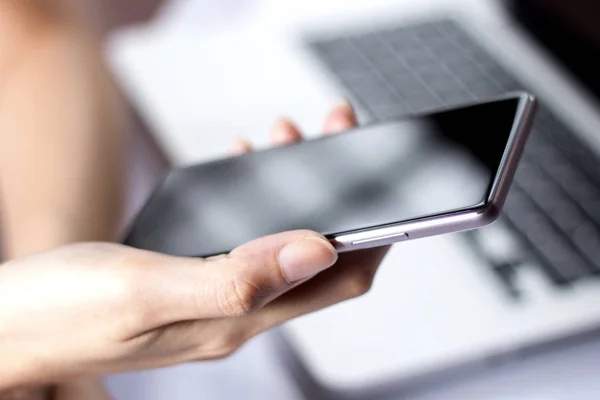 Mano que sostiene el teléfono inteligente móvil con pantalla en blanco . — Foto de Stock