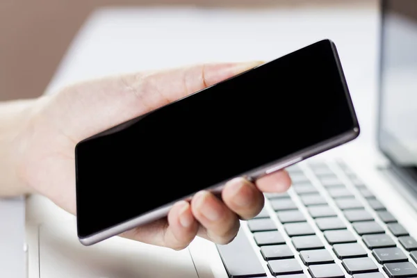 Mano que sostiene el teléfono inteligente móvil con pantalla en blanco . — Foto de Stock