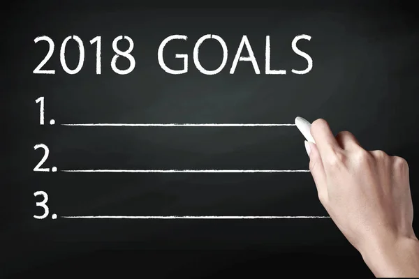 Mano sosteniendo una tiza y escribiendo objetivos de 2018 —  Fotos de Stock