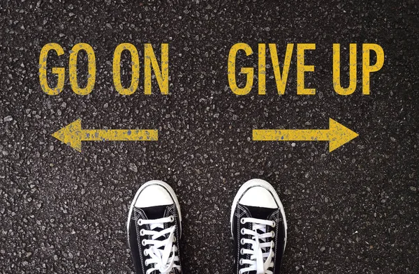 Black shoes standing at the road with go on and give up wording. — Stock Photo, Image