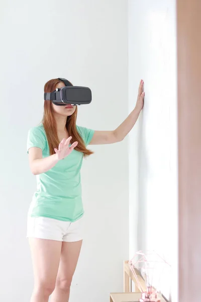 Jeune femme portant des lunettes de réalité virtuelle à la maison . — Photo