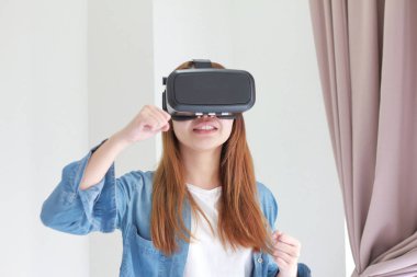 Evde sanal gerçeklik gözlüklü genç kadın.