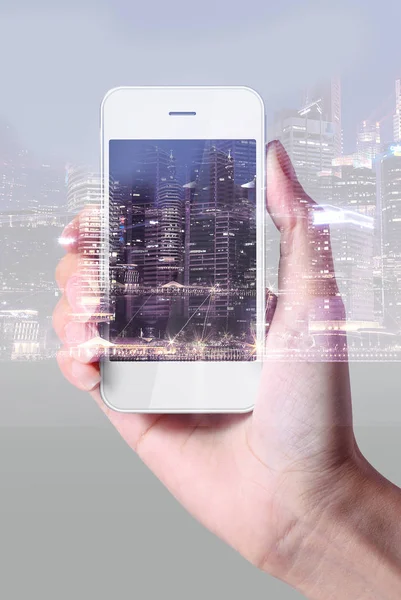 Рука с помощью смартфона на фоне городского пейзажа — стоковое фото