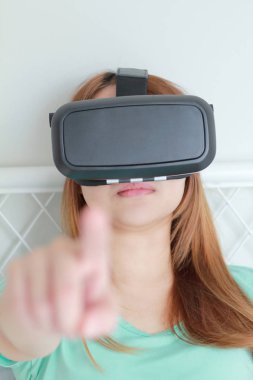 Evde sanal gerçeklik gözlüklü genç kadın.