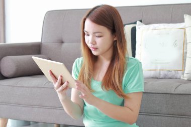 Evde tablet kullanan genç bir kadın..