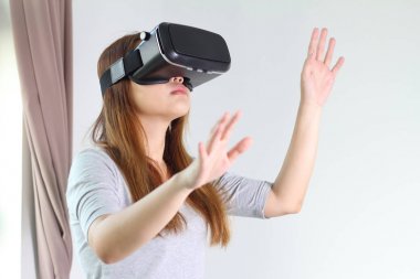 Evde sanal gerçeklik gözlüklü genç kadın.