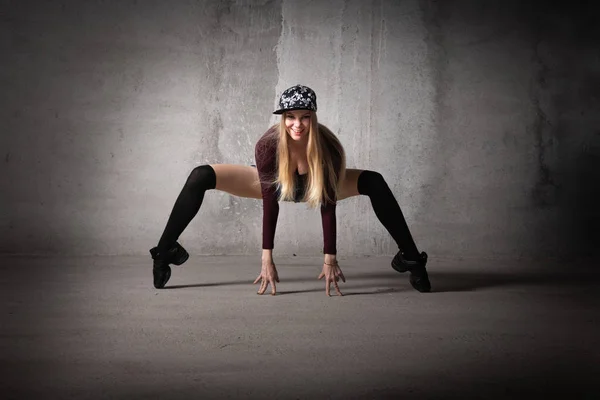 Dancer in a dance pose on a gray background. Blonde dancer with long hair in a sexy pose. Feet, dance, modern dance, hip hop, classical dance, stretching, active, fitness body